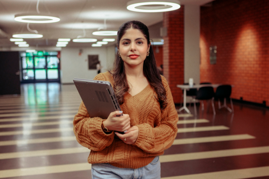 A female student with laptop at a university corridor