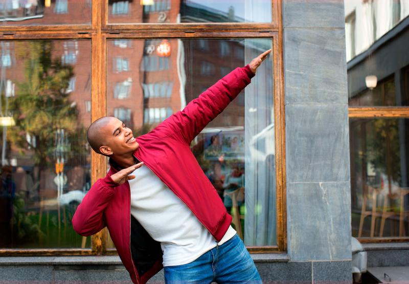 A picture of a student joyfully posing in front of some windows