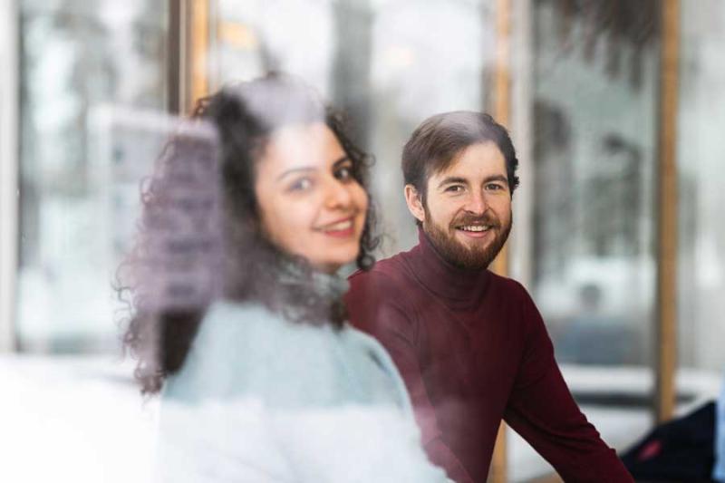 Students sitting at a table and smiling through a window