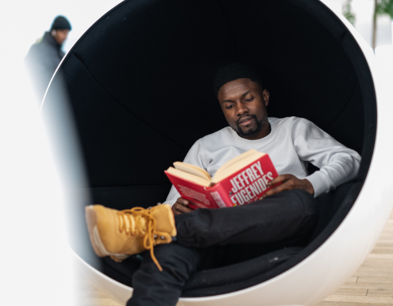 Student sitting in a spherical chair and reading