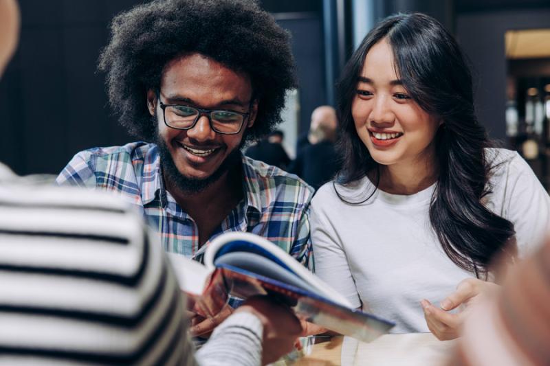 Two happy students studying with a book