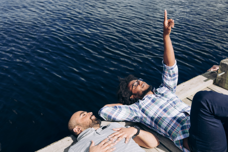 Two students lying on their backs on a pier, looking up at the sky
