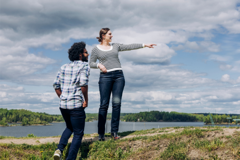 Two persons standing on a cliff, the other pointing direction