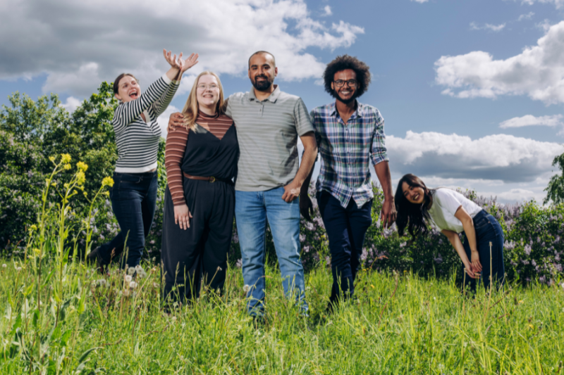A group of students standing in a green, sunlit field in summer