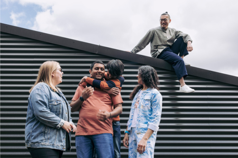 A group of students gathered outside near a wall