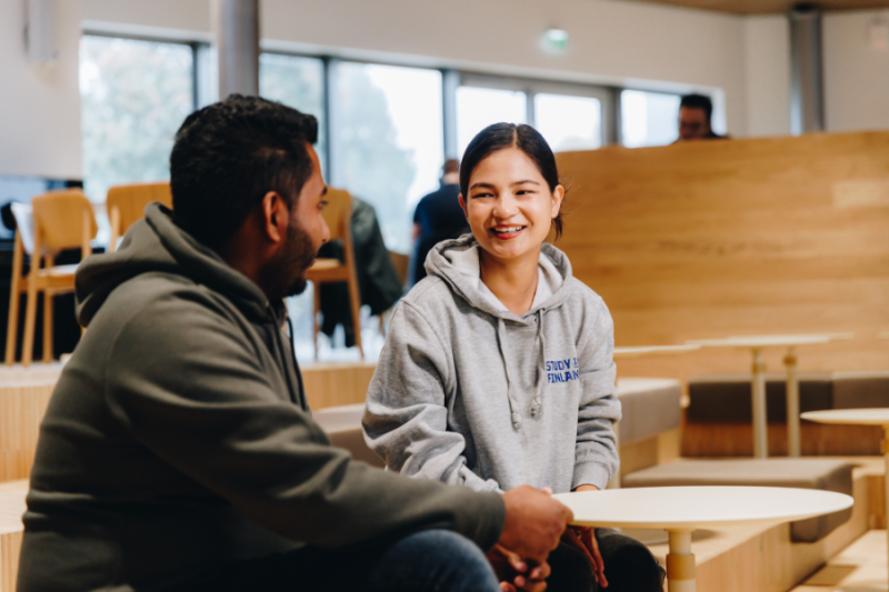 Two students chatting at university cafeteria table
