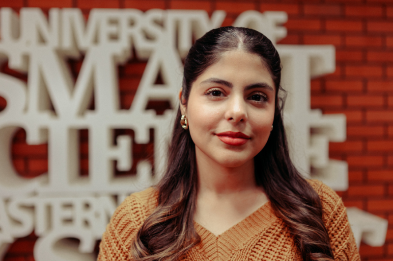 A female student in front of a university promo text